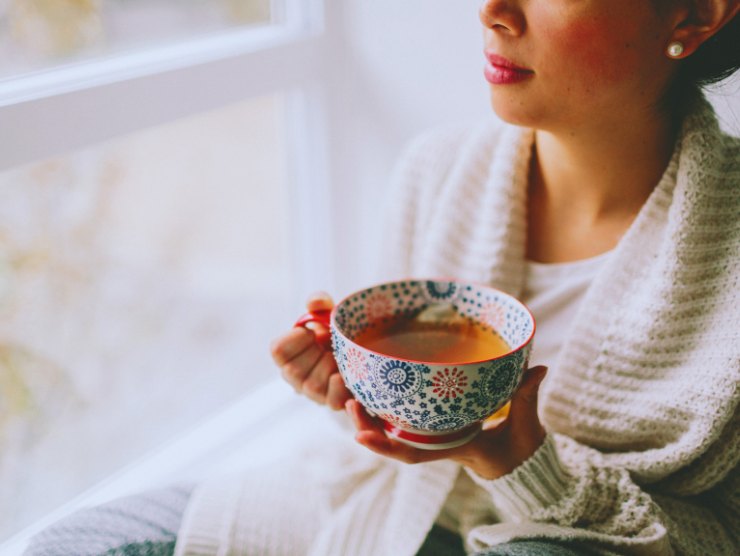 donna alla finestra con tazza di tè in mano